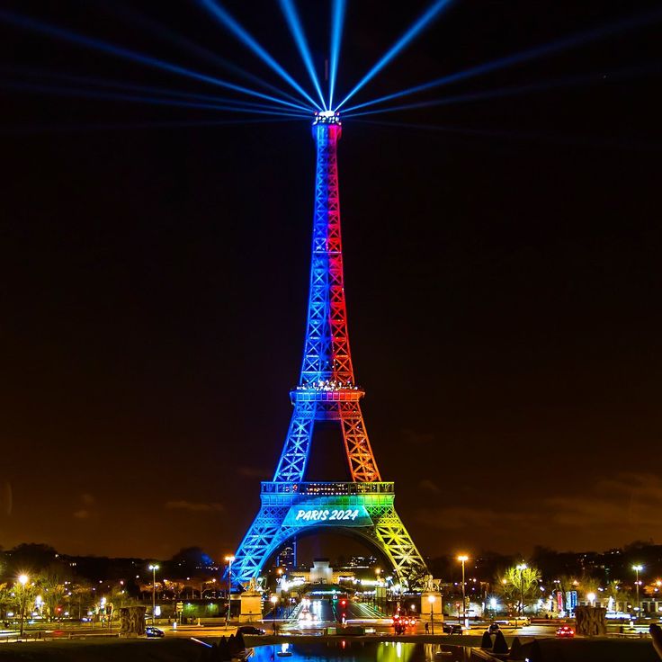 the eiffel tower is lit up in blue, red and green colors at night