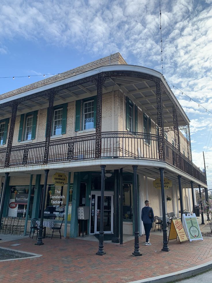 an old fashioned building on the corner of a street in front of a man walking by