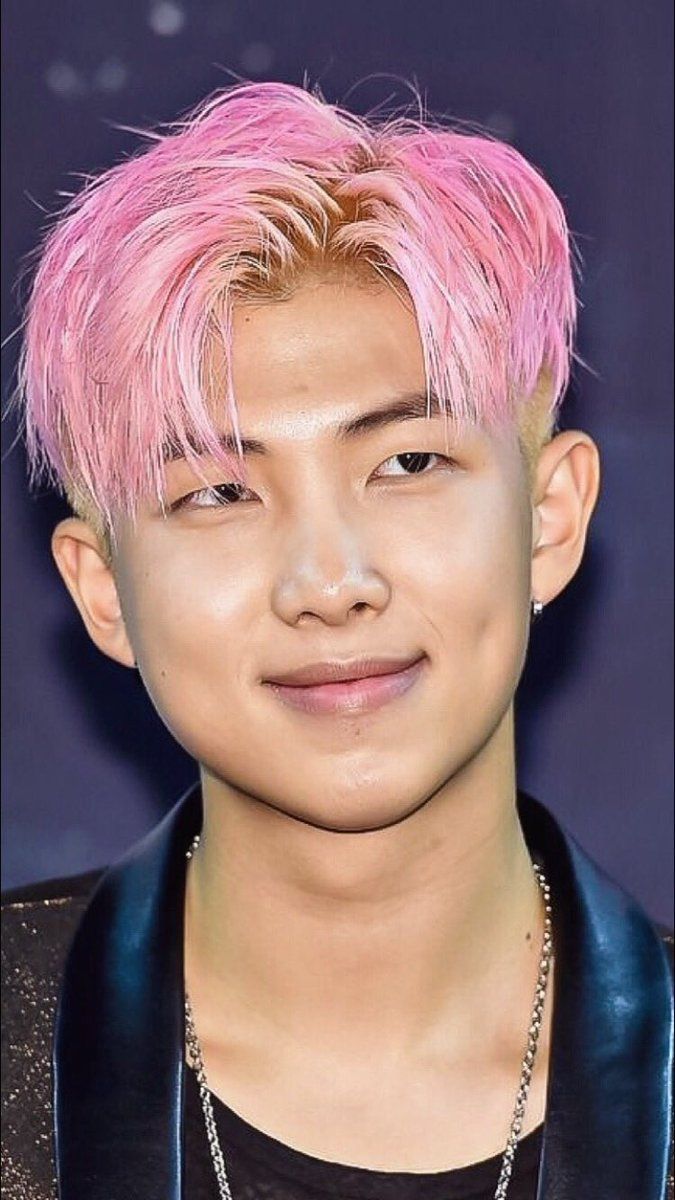 a young man with pink hair wearing a black shirt and silver chain around his neck