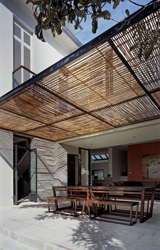 an outdoor dining area with wooden tables and chairs under a bamboo covering over the table