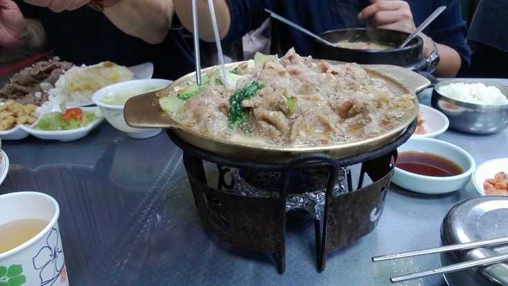 people sitting at a table with food in bowls and plates on the table, eating