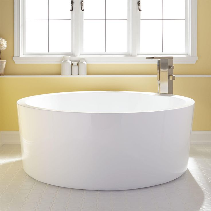 a white bath tub sitting next to a window in a yellow bathroom with two windows