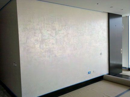 an empty room with a mattress on the floor in front of a large white wall