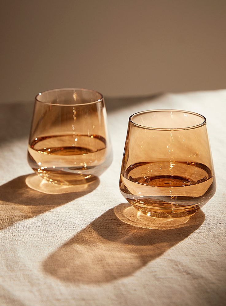 two glasses sitting next to each other on top of a white cloth covered tablecloth