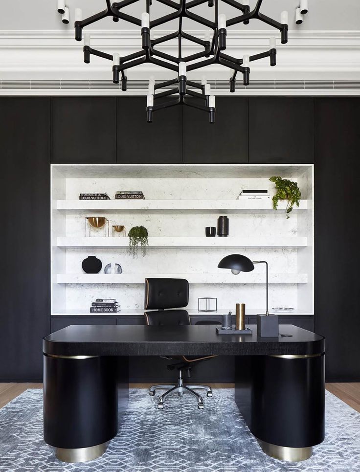 an office with black and white decor, including a large desk in front of a bookcase