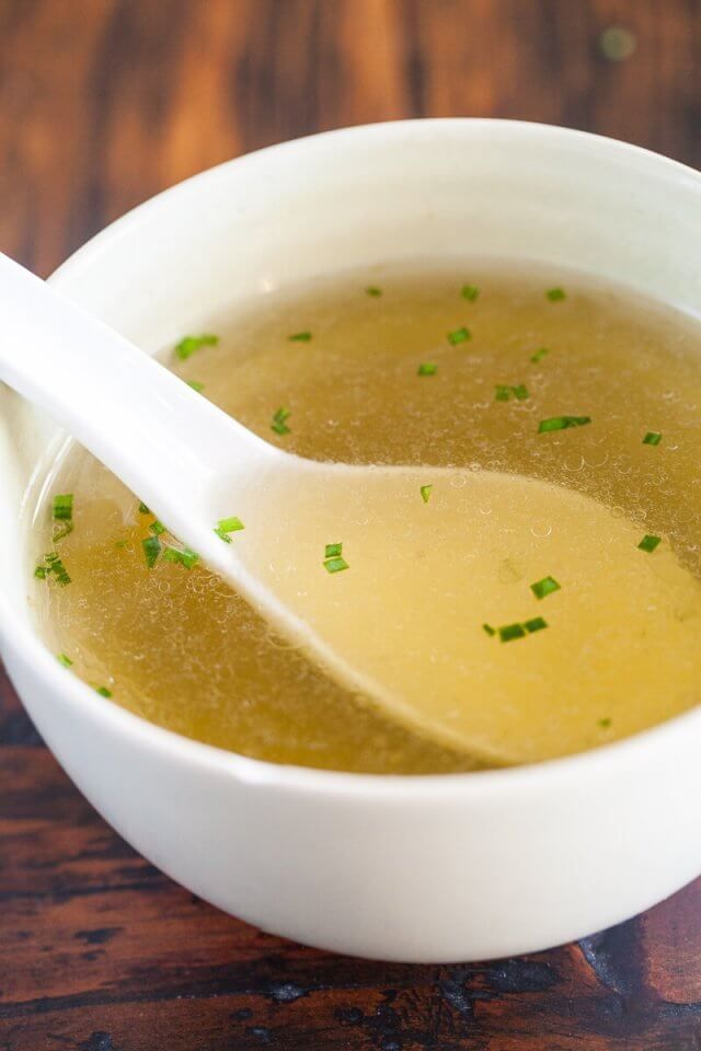 a white bowl filled with soup on top of a wooden table next to a spoon