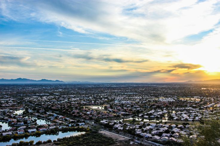 an aerial view of a city with mountains in the distance and water at sunset or sunrise