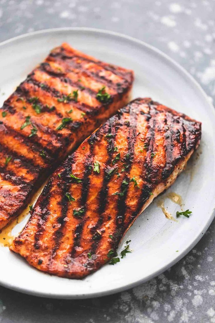 two pieces of grilled salmon on a white plate