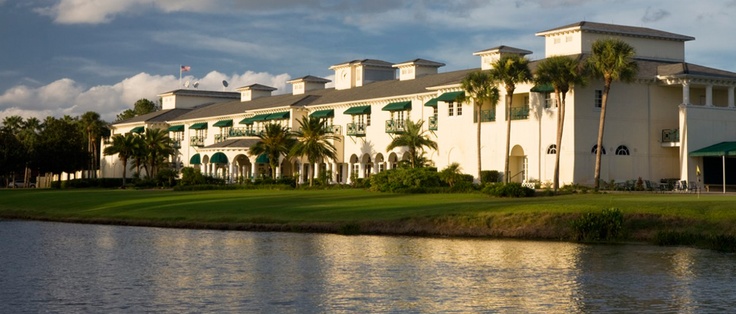 a large white building next to a body of water with palm trees in the foreground