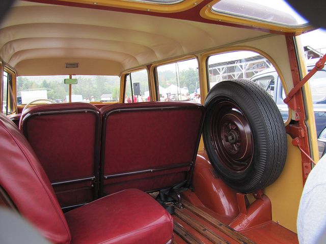 the interior of an old fashioned bus with red seats and a large tire on it