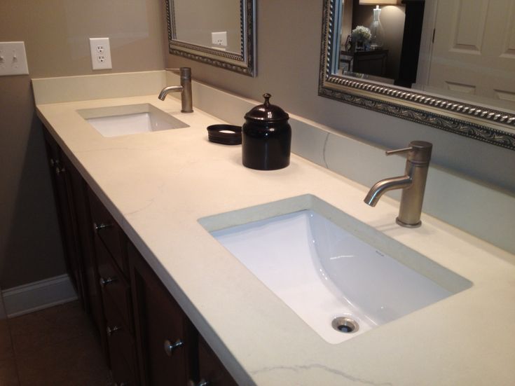 a bathroom counter with two sinks and mirrors