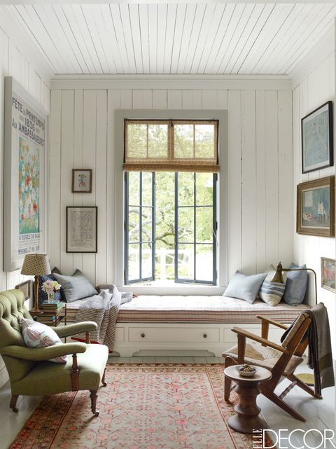 a living room filled with furniture next to a window covered in pictures and framed art