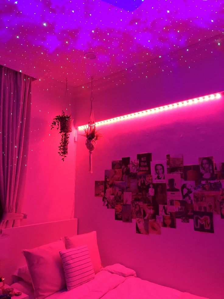 a bedroom with pink lights and pictures on the wall above it, along with a bed