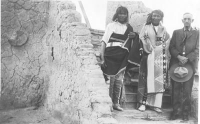 an old black and white photo of three people standing on the side of a building