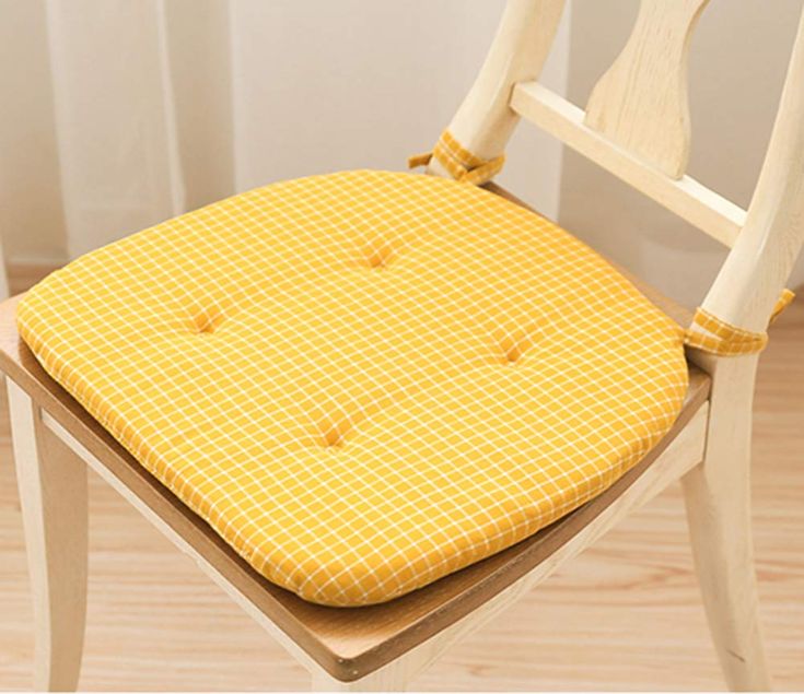 a wooden chair with a yellow seat pad on it's back and the seat cushion is up