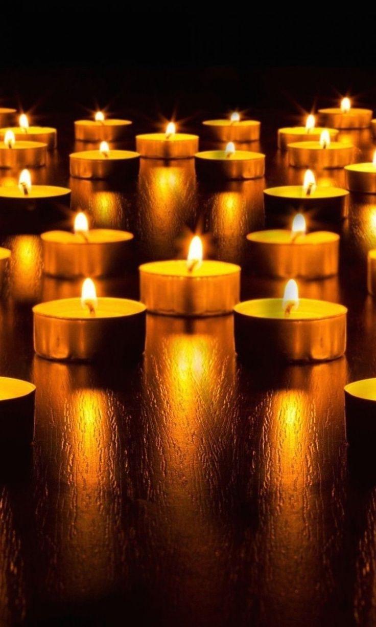 rows of lit candles sitting on top of a table