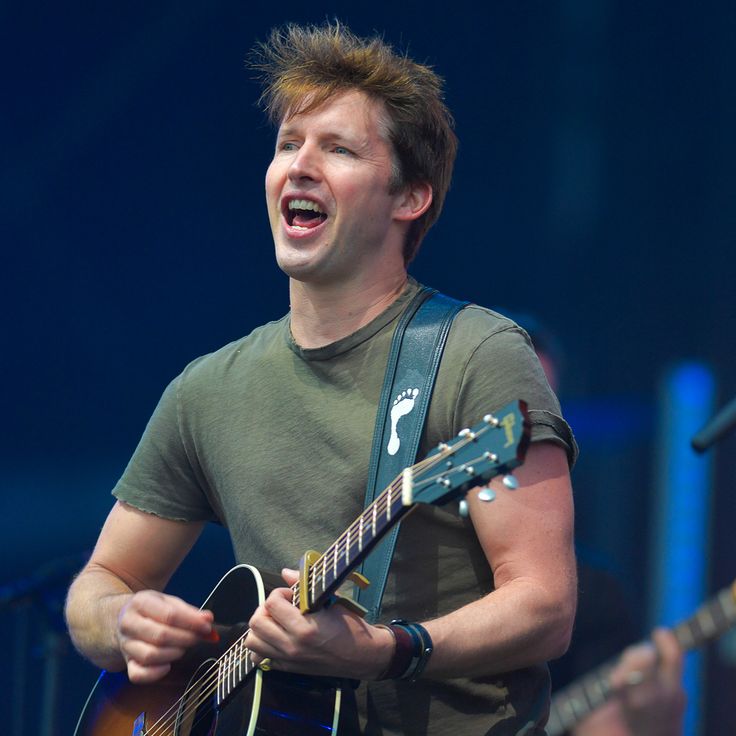 a man with an open mouth and guitar in his hands, singing into the microphone