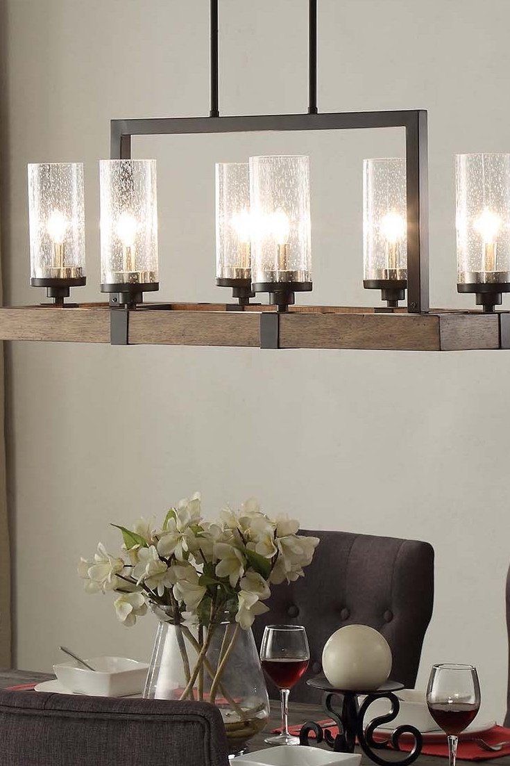 a chandelier hanging over a dining room table with wine glasses and flowers on it