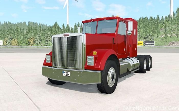 a red semi truck parked in front of a wind turbine