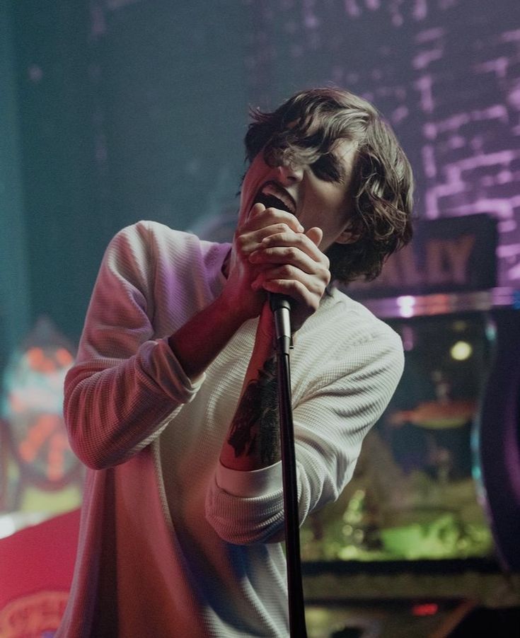 a man holding a microphone up to his mouth while standing in front of a stage