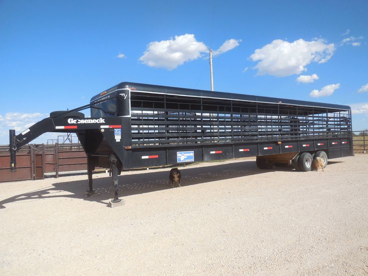 a large black trailer parked on top of a dirt field