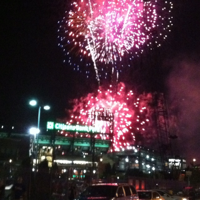 fireworks are lit up in the night sky over a parking lot with cars parked on it