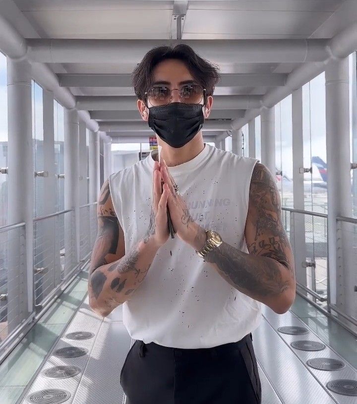 a man wearing a face mask standing in a hallway with his hands folded up to pray