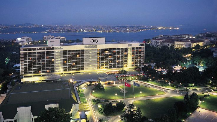 an aerial view of a hotel at night with the city lights lit up in the background