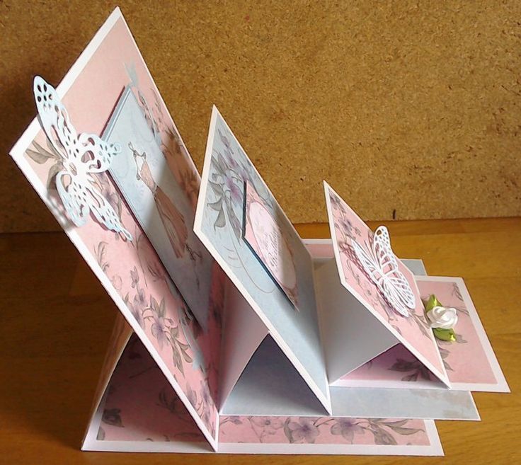 an open pink and white folded card with flowers on it, sitting on a wooden table