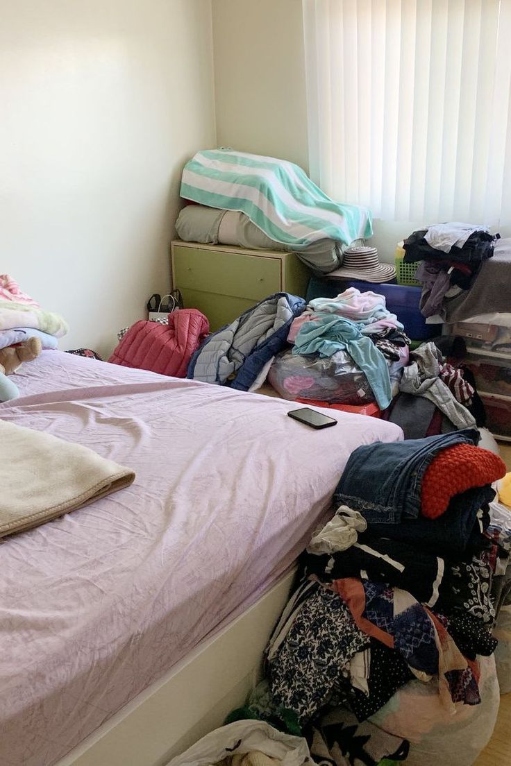 an unmade bed with lots of clothes on it