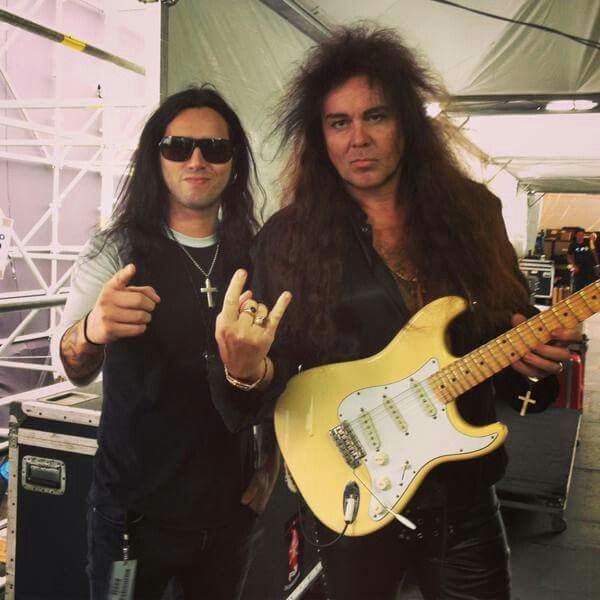 two men standing next to each other with guitars in their hands and one holding the peace sign