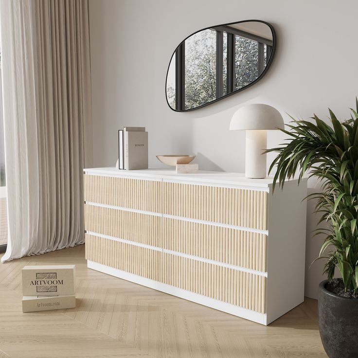 a living room with a plant and a mirror on the wall above it's dresser