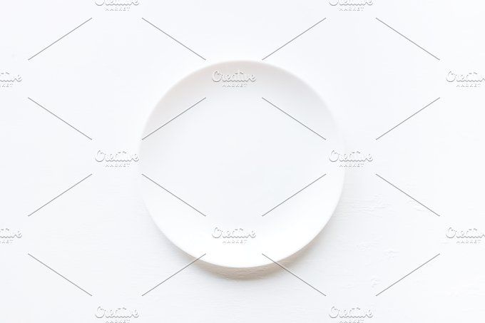 a white plate on a white table top view with copy space in the middle, flat layed out