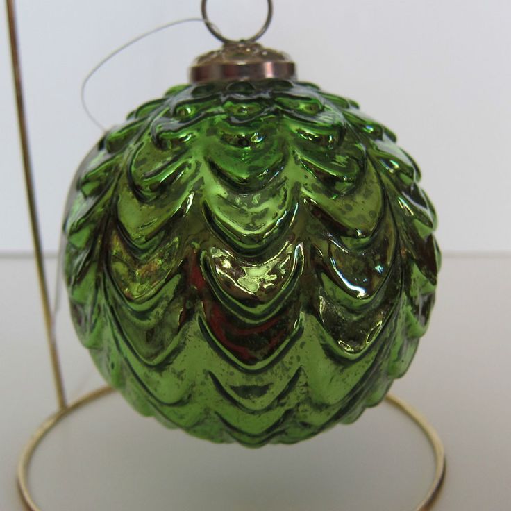 a green glass ornament sitting on top of a stand