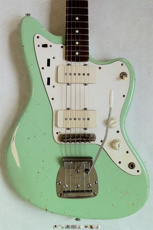 an electric guitar is sitting on a white surface with a green body and pick - up