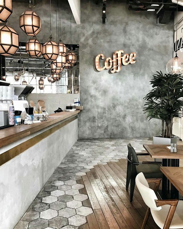 the interior of a coffee shop with wooden tables and chairs, hanging lights, and potted plants