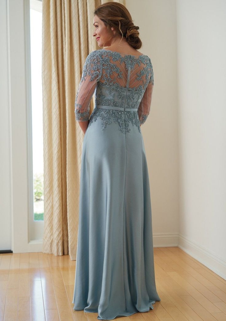 a woman in a long blue dress standing on a hard wood floor with her back to the camera