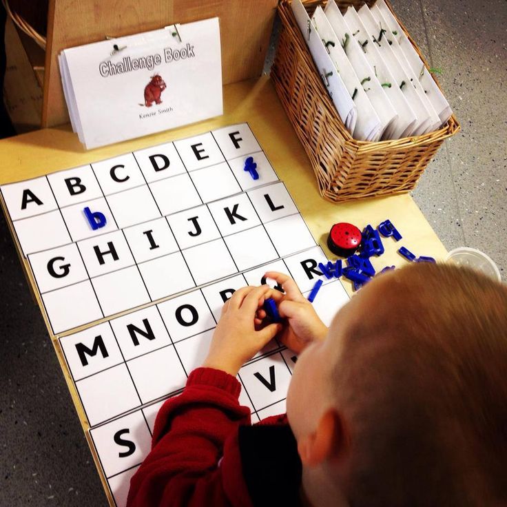 a young boy is playing with letters and numbers on a board game set up for children to play