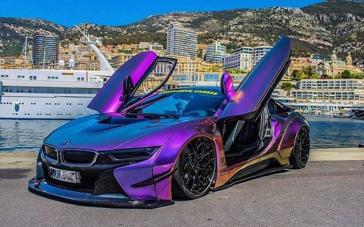 a purple car with its doors open next to the water