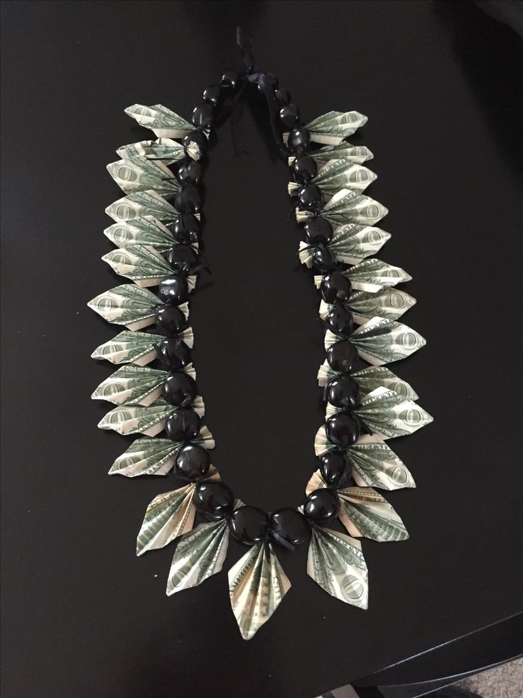 a black and white necklace with leaves on it's end, sitting on top of a table