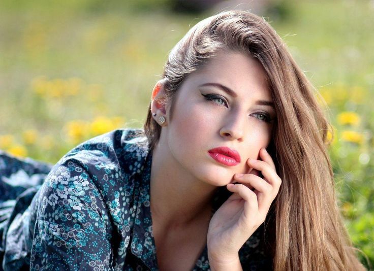 a woman laying on the ground with her hand under her chin and looking at the camera