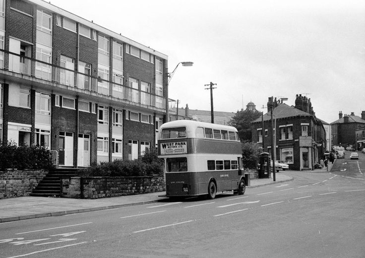 a double decker bus is driving down the street in front of an apartment building with balconies