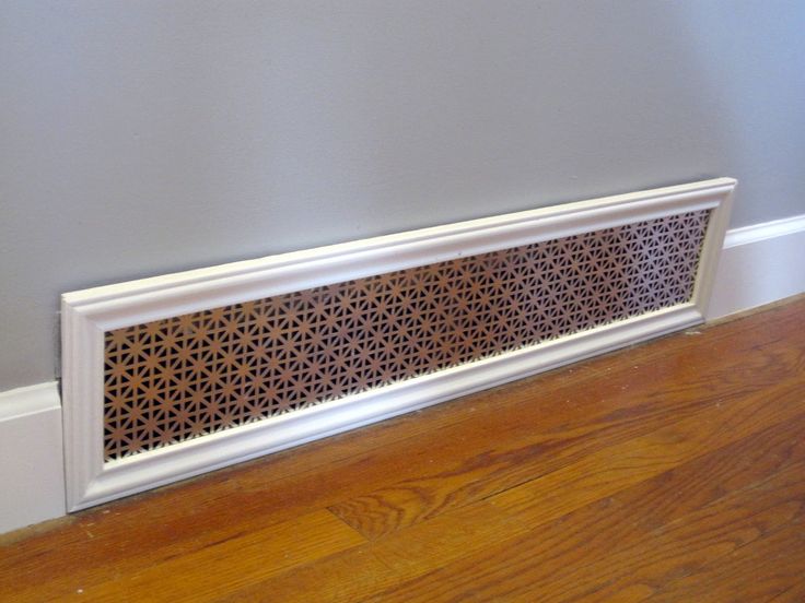 a white radiator cover sitting on top of a hard wood floor next to a wall