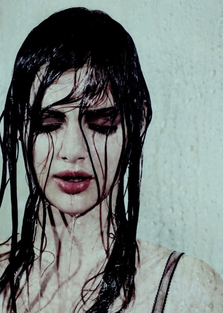 a woman with wet hair standing in front of a wall