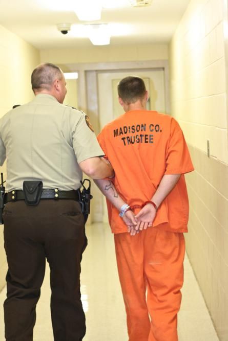 two men in orange prison uniforms walking down a hallway