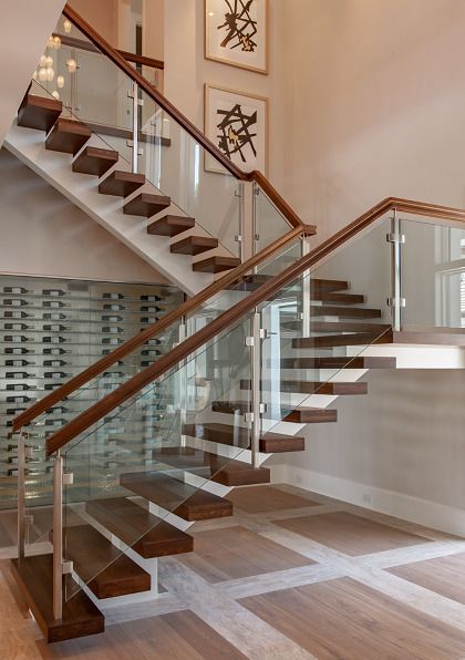 a staircase with glass railing and wooden handrails in a home interior area,