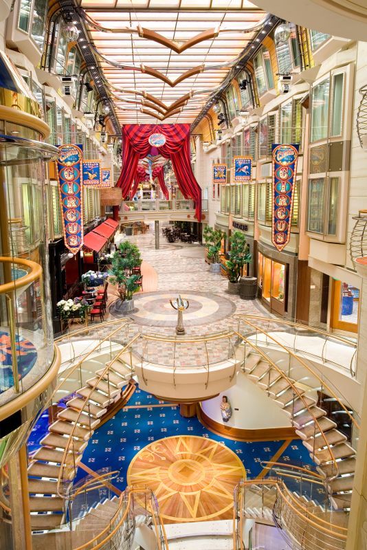 the inside of a cruise ship with many tables and chairs on each side of the walkway