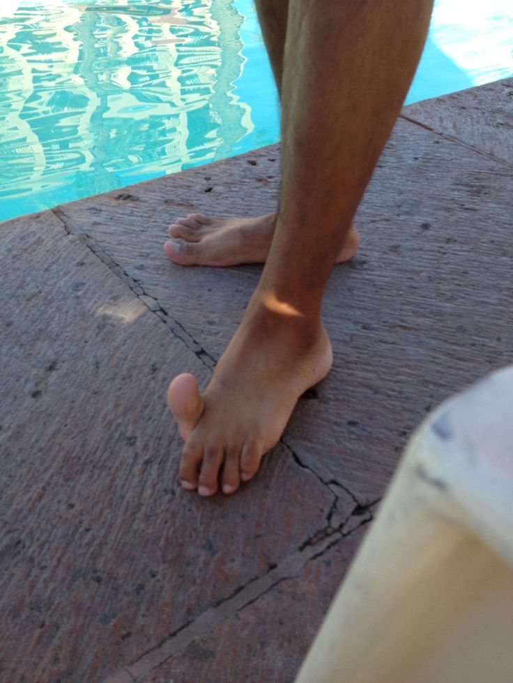 a man standing next to a swimming pool with his bare feet