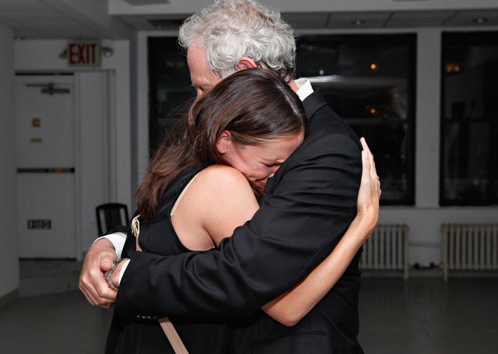 a man and woman hugging each other in a room with white carpeted flooring