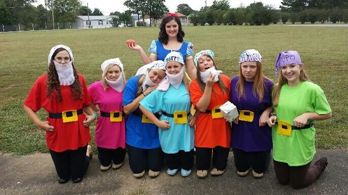 a group of women dressed in costumes standing next to each other on top of a field